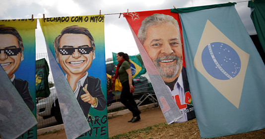 A woman walks past presidential campaign materials depicting Brazil's former President Luiz Inacio Lula da Silva and and President Jair Bolsonaro in Brasilia, Brazil, September 23, 2022.